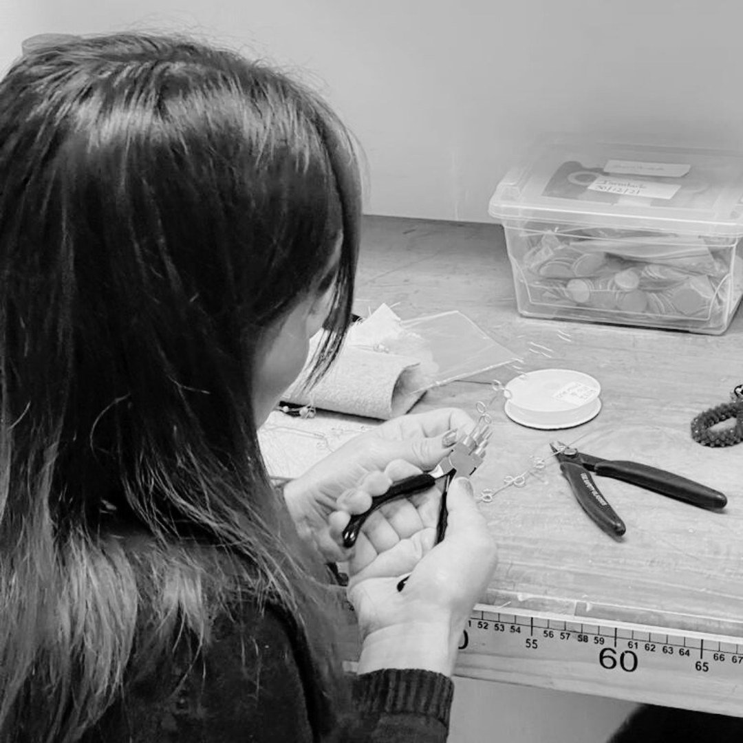 Woman with a tool on her hand working on handmade earrings 