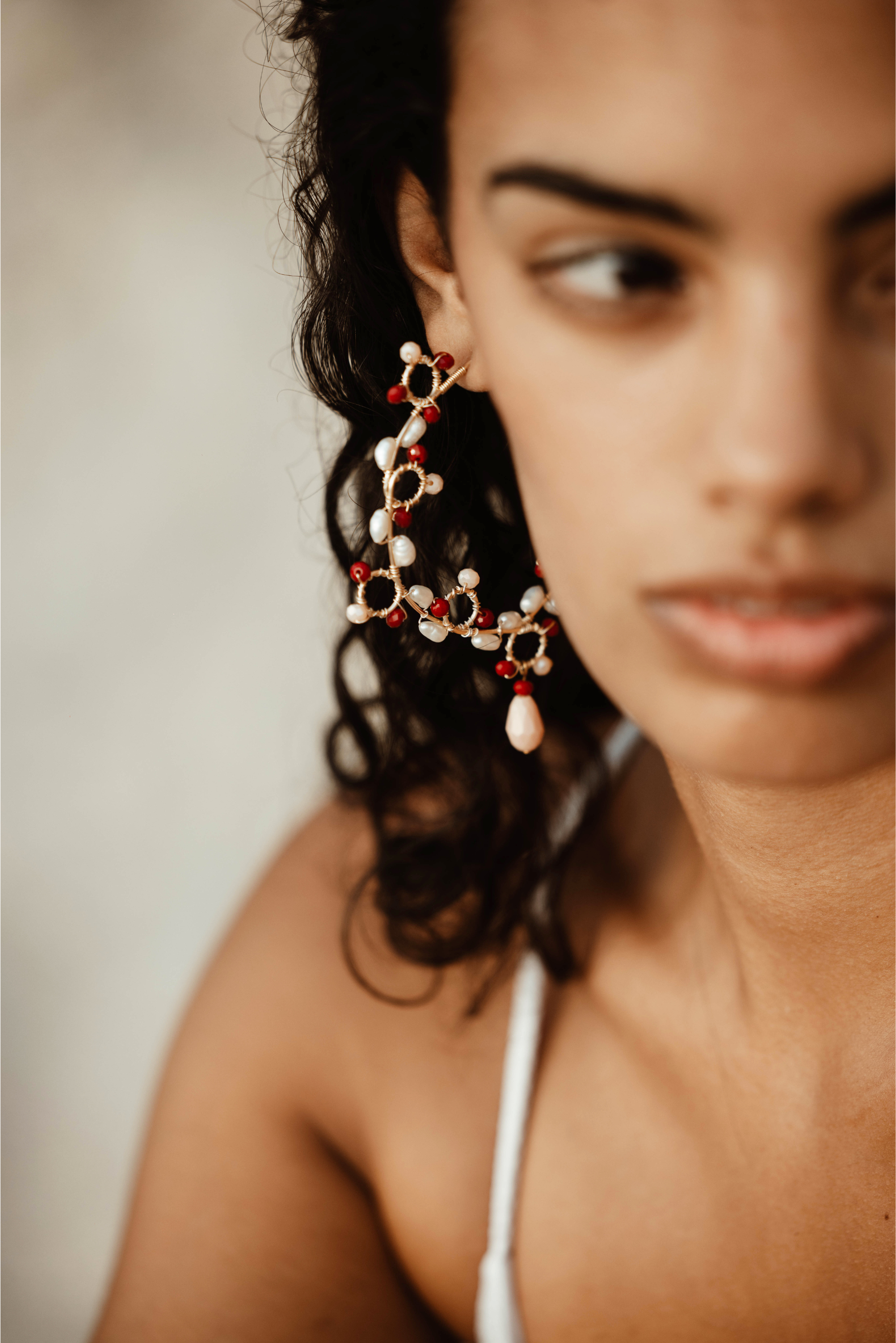 Close-up of a woman wearing intricate earrings with a neutral background