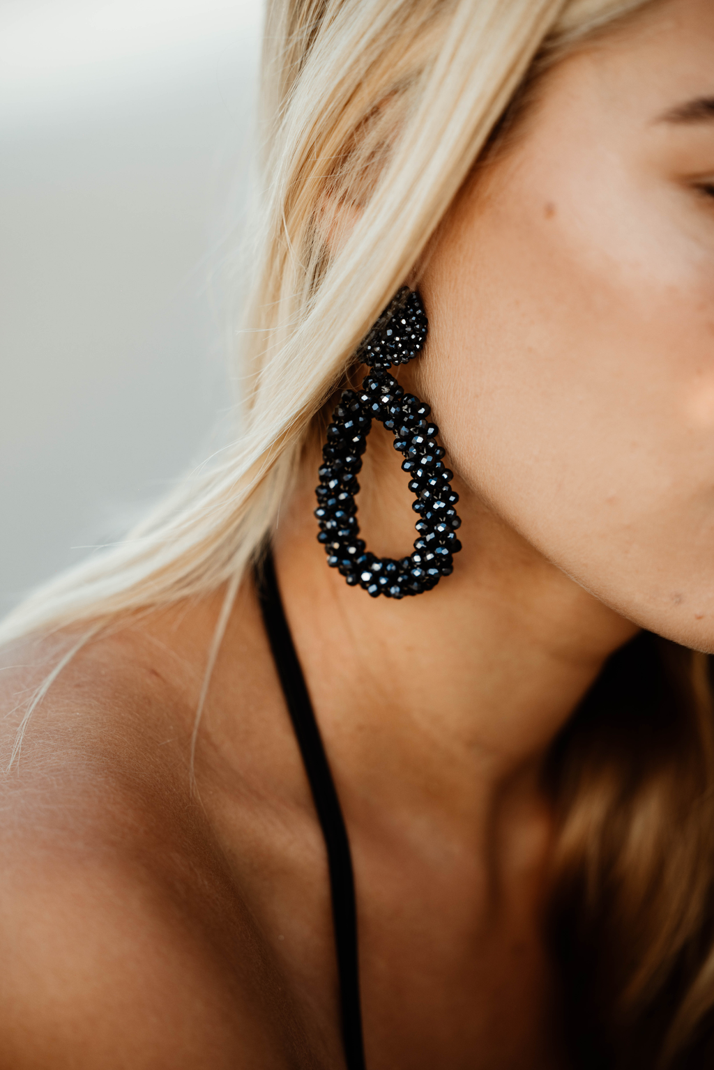 Close-up of a person wearing black beaded earrings with a blurred background