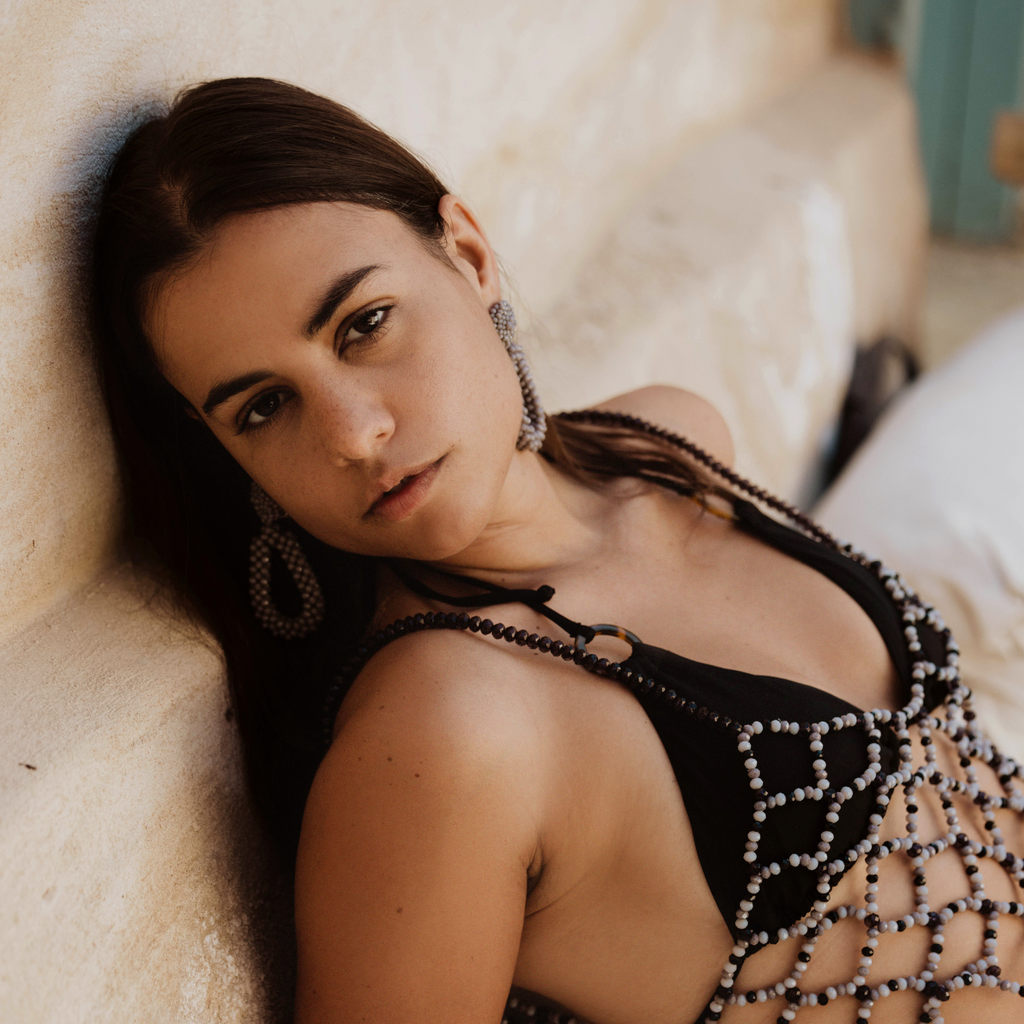 Woman wearing a black beaded outfit lying on a textured surface