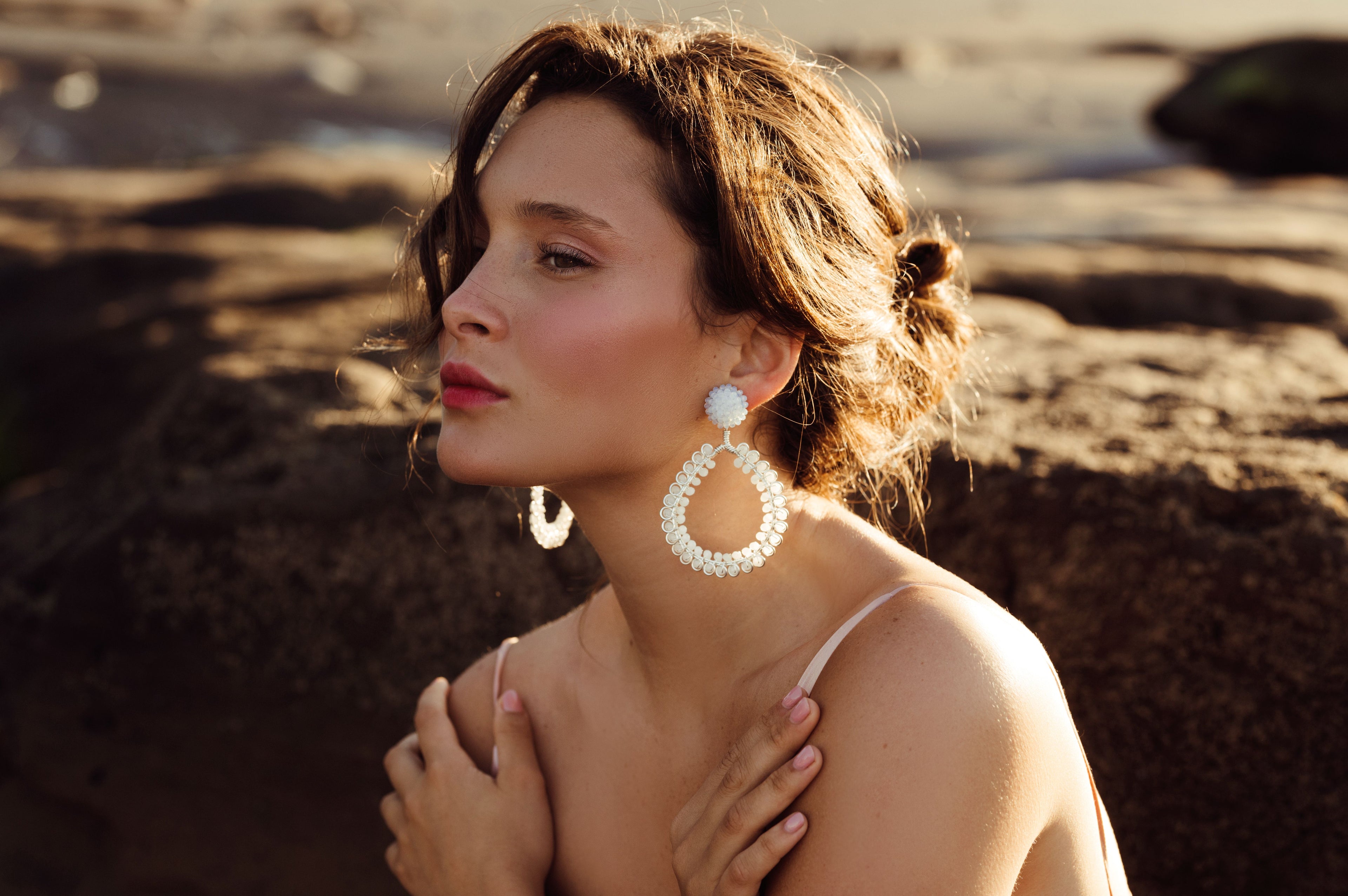 Woman wearing large hoop earrings on a beach